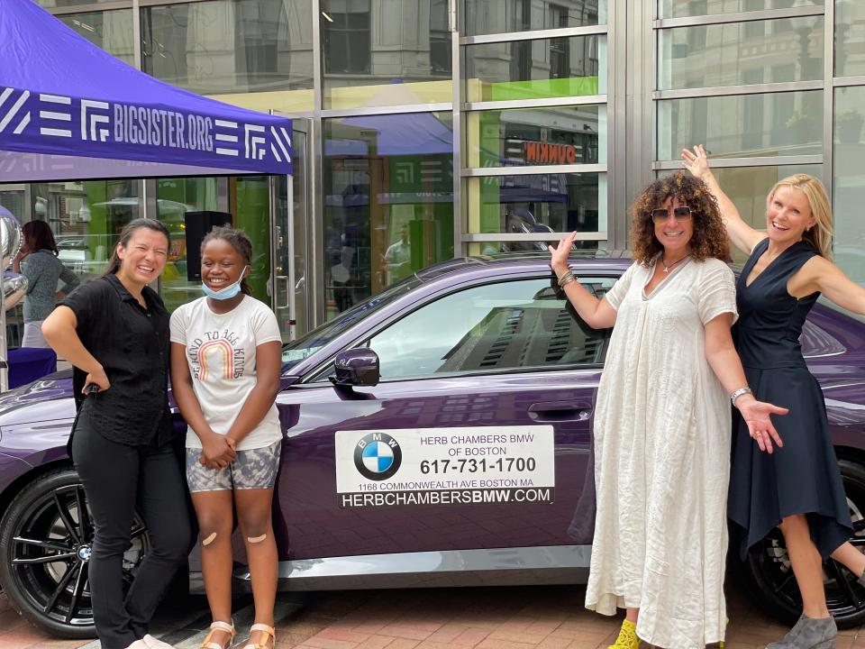 Tara Reddington said the BMW's purple color is what drew her attention since it was a color her family long associated with Grace. Here, Big sister Aiko, Little Sister Nekelah, Herb Chambers BMW of Boston general manager Melissa Steffy, and WBZ TV anchor Lisa Hughes, a board member who emceed the event, pose by the car during Thursday's drawing.
