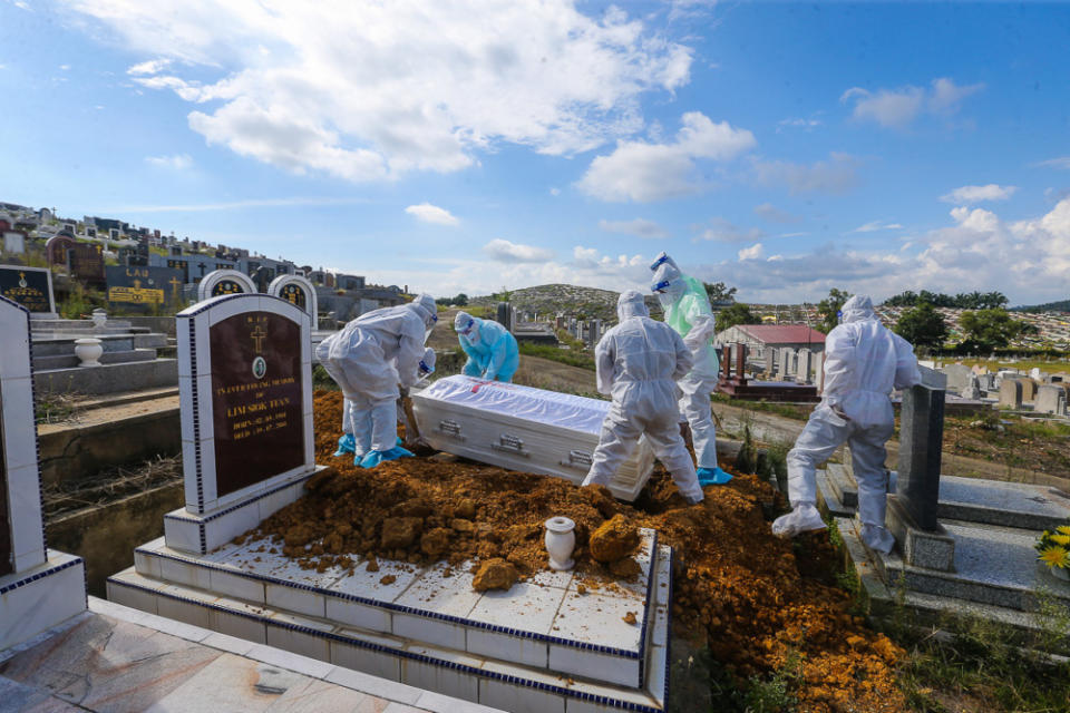 Workers wearing personal protective equipment carry a coffin containing the body of a person who died from Covid-19 at the Meru Christian Cemetery in Klang, August 9, 2021. ― Picture by Yusof Mat Isa