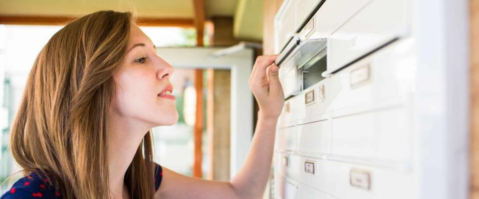 Pretty, young woman checking her mailbox for new letters