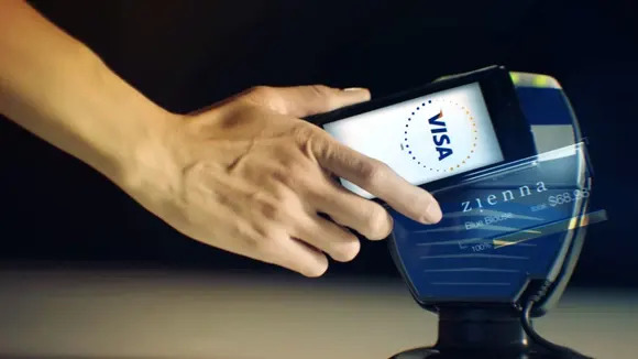 A woman uses her smartphone to buy merchandise with a Visa card.