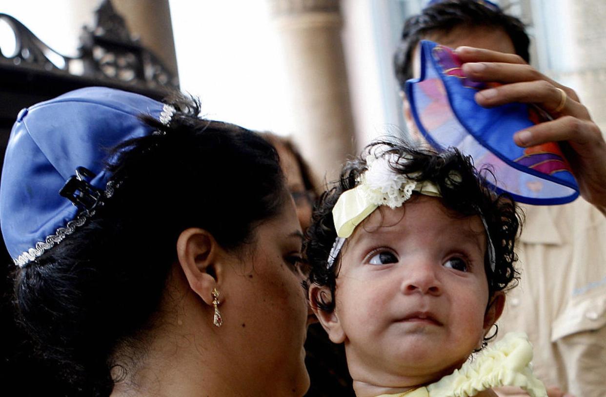 Jewish mothers have created ways to celebrate childbirth with rituals old and new. <a href="https://www.gettyimages.com/detail/news-photo/young-indian-jewish-child-naomi-is-carried-by-her-mother-as-news-photo/76710231?adppopup=true" rel="nofollow noopener" target="_blank" data-ylk="slk:Pal Pillai/AFP via Getty Images;elm:context_link;itc:0;sec:content-canvas" class="link ">Pal Pillai/AFP via Getty Images</a>