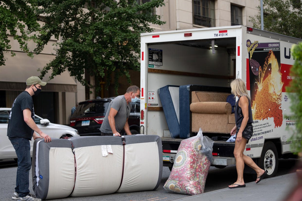 People wearing masks load furniture into a U-haul moving truck in New York City. (Photo by Alexi Rosenfeld/Getty Images)