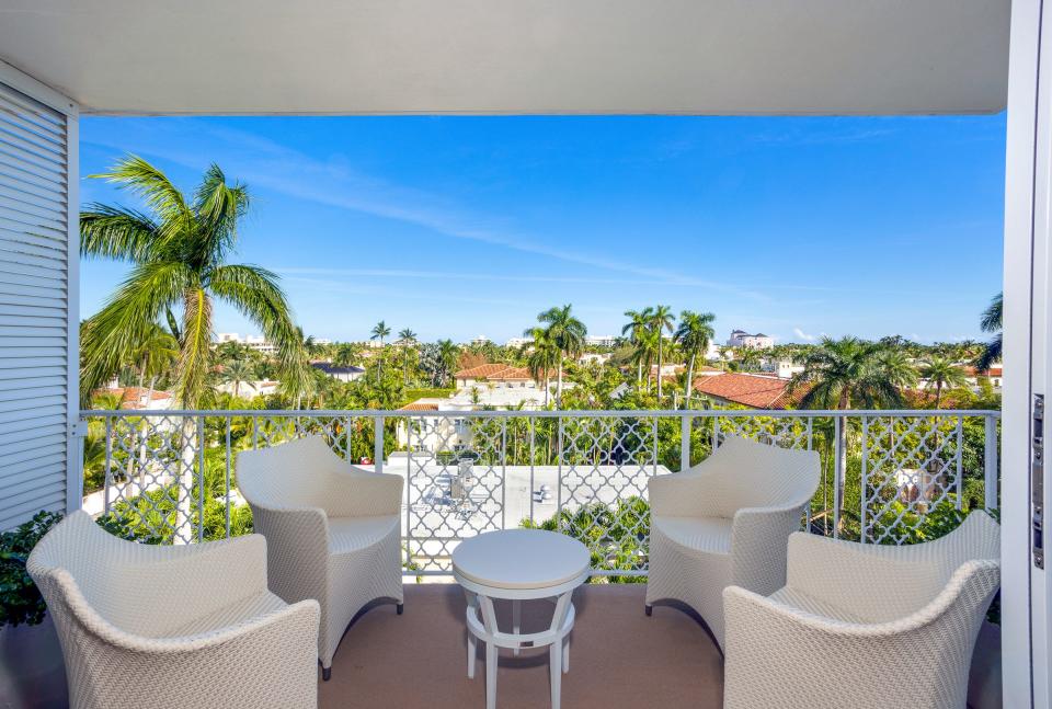 Furnished for alfresco dining, the balcony looks out to neighboring buildngs with barrel-tile roofs.