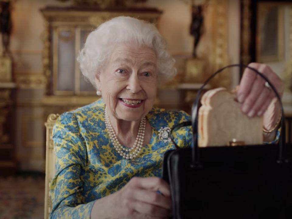 A still from the Queen's short movie with Paddington, showing her pulling a marmalade sandwich out of her handbag.
