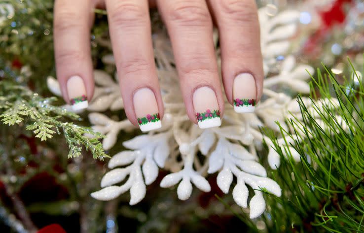 a french manicure with leaves and berries in between the nail beds and the tips