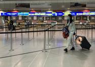 FILE PHOTO: A passenger wearing a face covering walks past the Ryanair check-in desks at Manchester Airport following the outbreak of the coronavirus disease (COVID-19) in Manchester, Britain