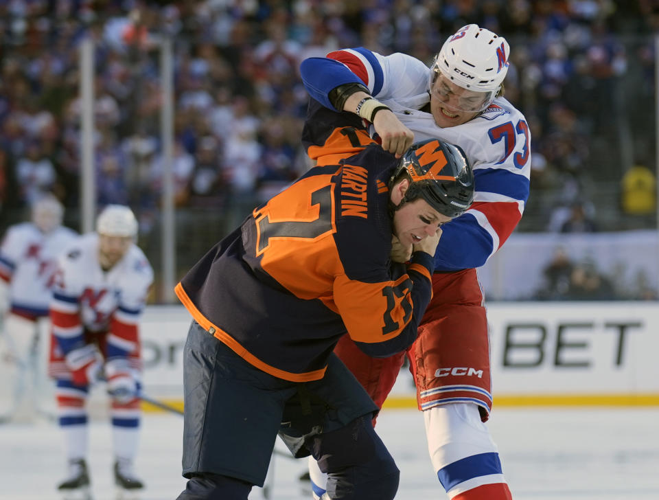 FILE - New York Rangers' Matt Rempe, top, fights with New York Islanders' Matt Martin, bottom, during the first period of an NHL Stadium Series hockey game in East Rutherford, N.J., Feb. 18, 2024. Rempe fought seconds into his first NHL shift. Rangers fans chant his name whether he is playing or not. The 6-foot-8 forward was a central figure in a rare line brawl. And at 21 he has become a modern-day cult hockey hero. (AP Photo/Seth Wenig, File)