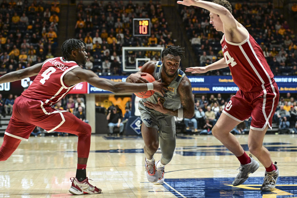 West Virginia guard Joe Toussaint, center, protects the ball from Oklahoma guard Joe Bamisile (4) and forward Jacob Groves, right, during the first half of an NCAA college basketball game in Morgantown, W.Va., Saturday, Feb. 4, 2023. (AP Photo/William Wotring)