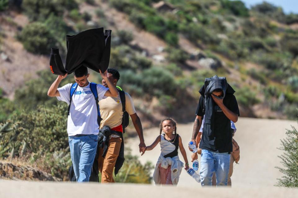 People carry belongings on a desert terrain