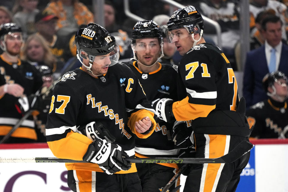 Pittsburgh Penguins' Sidney Crosby (87) looks at his wrist as he prepares for a faceoff after being slashed during the second period of the team's NHL hockey game against the Columbus Blue Jackets in Pittsburgh, Thursday, March 28, 2024. With him are Evgeni Malkin (71) and Michael Bunting, center. (AP Photo/Gene J. Puskar)