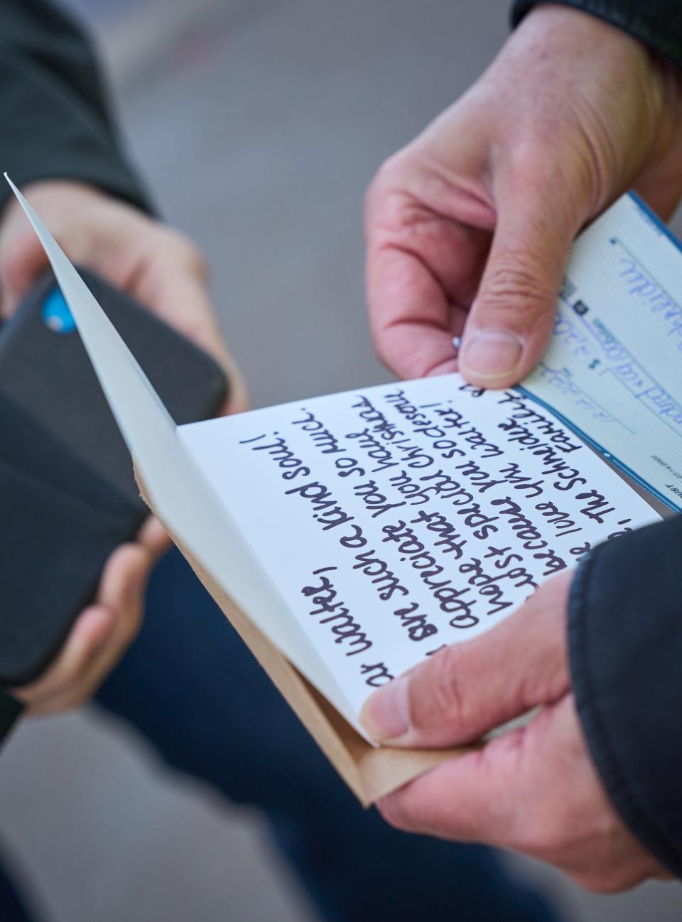 Walter Spano reads a card that was given to him by Mark and Lisa Schneider outside of Payne Junior High School in Queen Creek on Dec. 12, 2022.