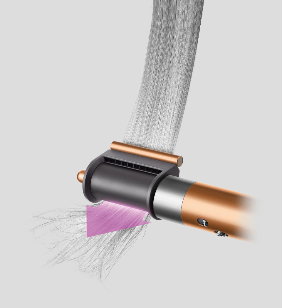 <p>An illustration of the Dyson Airwrap multi-styler 2022 with a barrel attachment and a strip of hair through it. A pink arrow indicates the direction the rod is going.</p>
