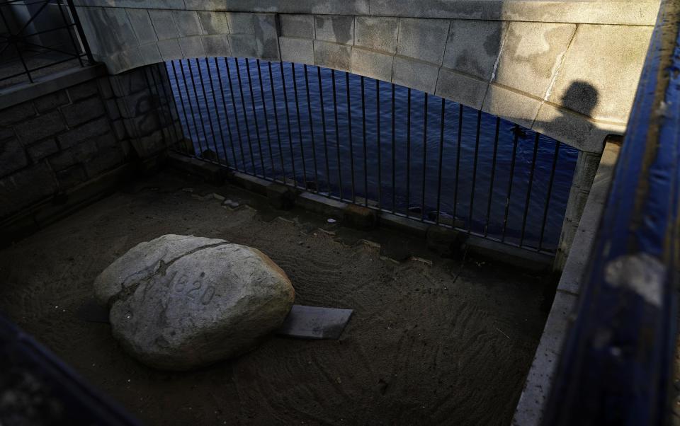 A visitor casts a shadow while looking at Plymouth Rock, the traditional point of arrival of the Pilgrims on the Mayflower in 1620, in Plymouth, Mass., Wednesday, Aug. 12, 2020. Disease introduced by traders and settlers, either by happenstance or intention, played an important role in the conquest of Native peoples. And that inconvenient fact, well known to the Natives' descendants, is contrary to the traditional narrative of the "New World." (AP Photo/David Goldman)