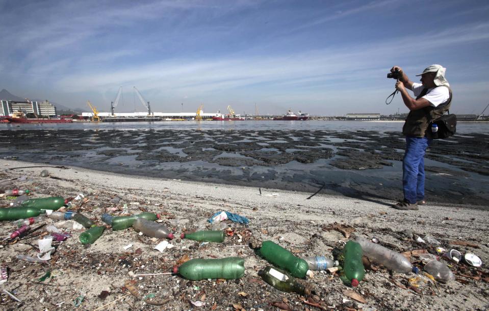 Brazilian biologist Mario Moscatelli takes pictures next to garbage at Pombeba island in the Guanabara Bay in Rio de Janeiro March 12, 2014. According to the local media, the city of Rio de Janeiro continues to face criticism locally and abroad that the bodies of water it plans to use for competition in the 2016 Olympic Games are too polluted to host events. Untreated sewage and trash frequently find their way into the Atlantic waters of Copacabana Beach and Guanabara Bay - both future sites to events such as marathon swimming, sailing and triathlon events. Picture taken on March 12, 2014. REUTERS/Sergio Moraes (BRAZIL - Tags: ENVIRONMENT SPORT OLYMPICS)