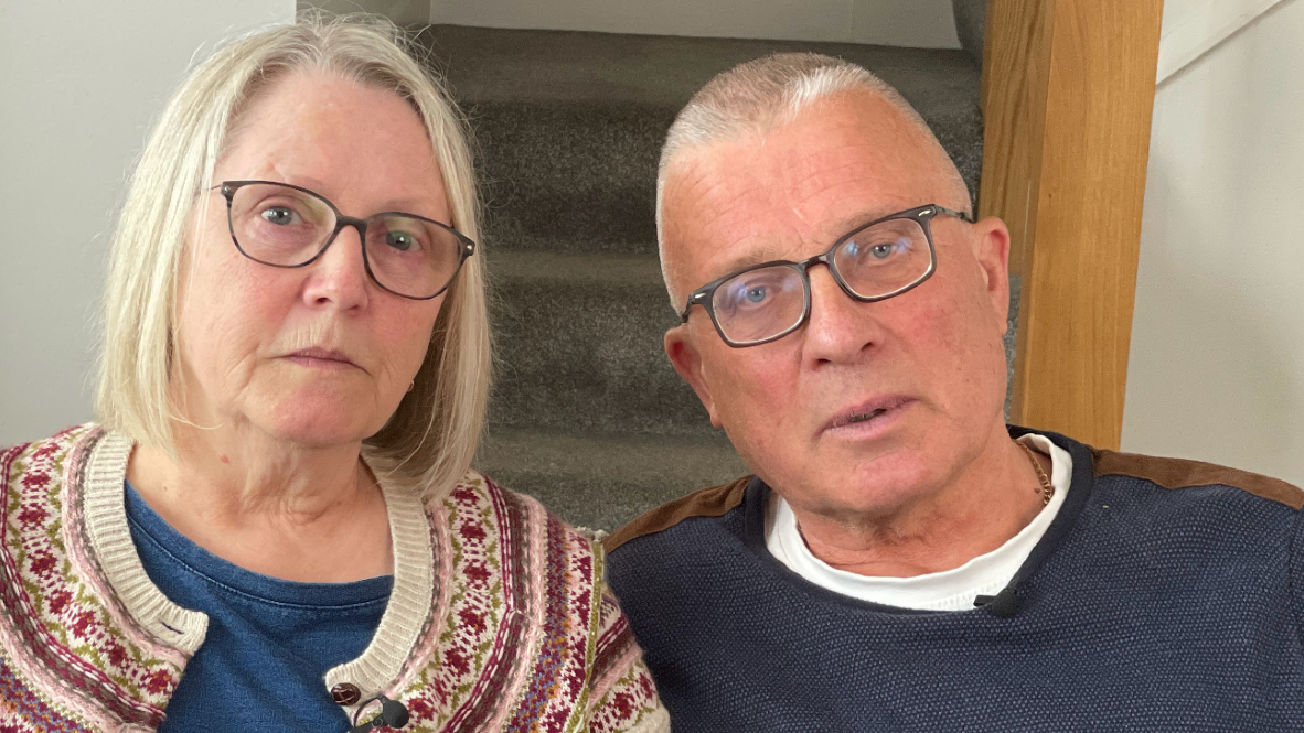 Denise and her husband Colin sitting looking at the camera