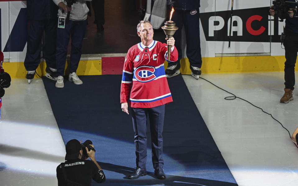 Former NHL player Pierre Turgeon holds a flame towards the crowd during a ceremony inducting him into the Montreal Canadiens' Ring of Honor prior to an NHL hockey game between the Canadiens and Calgary Flames in Montreal, Quebec, Tuesday, Nov. 14, 2023. (Graham Hughes/The Canadian Press via AP)