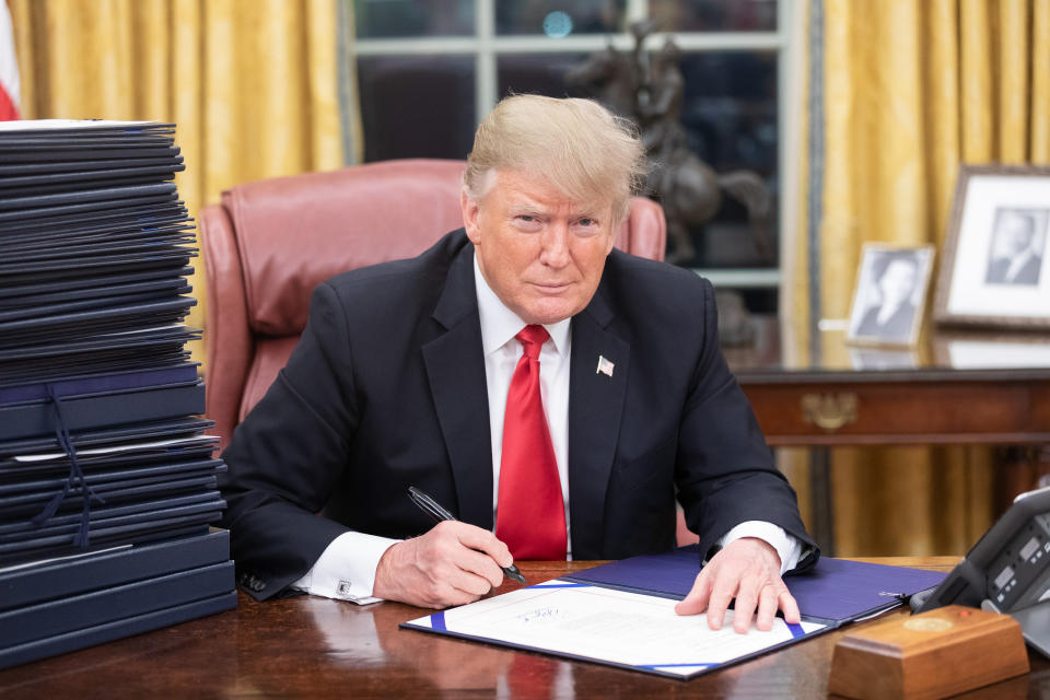 President Trump signing paperwork in the Oval Office.