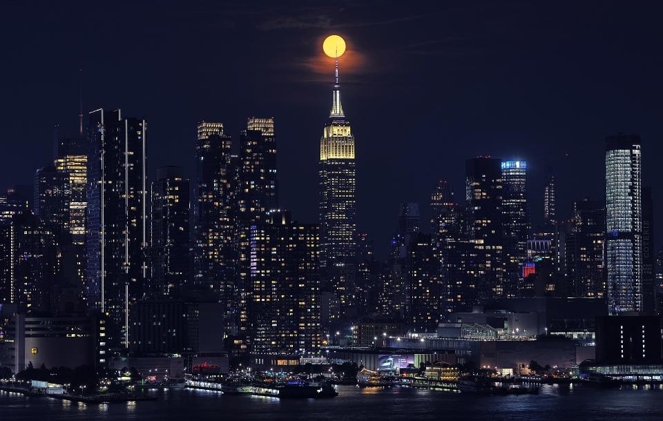 Der volle Erdbeermond geht am 21. Juni 2024 hinter dem Empire State Building in New York auf, von Weehawken, New Jersey aus gesehen.