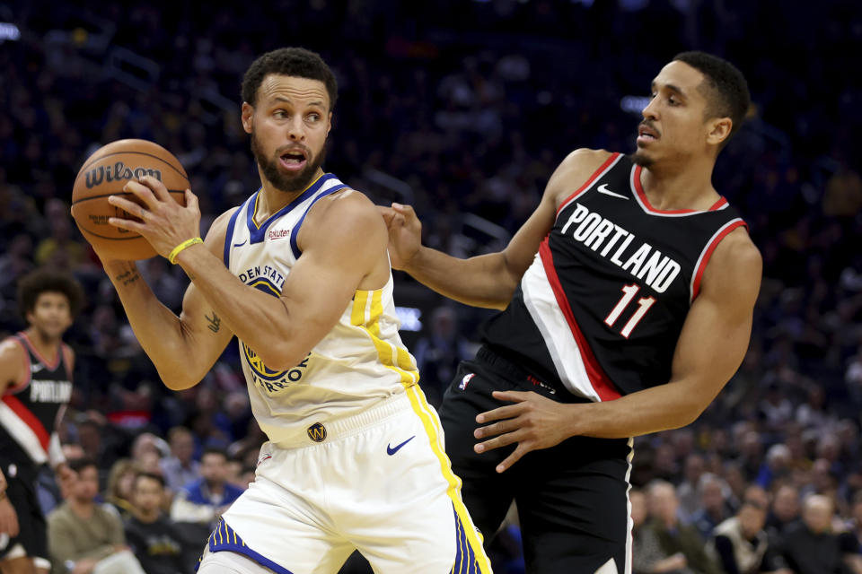 Golden State Warriors guard Stephen Curry grabs a rebound next to Portland Trail Blazers guard Malcolm Brogdon (11) during the first half of an NBA basketball game in San Francisco, Wednesday, Dec. 6, 2023. (AP Photo/Jed Jacobsohn)