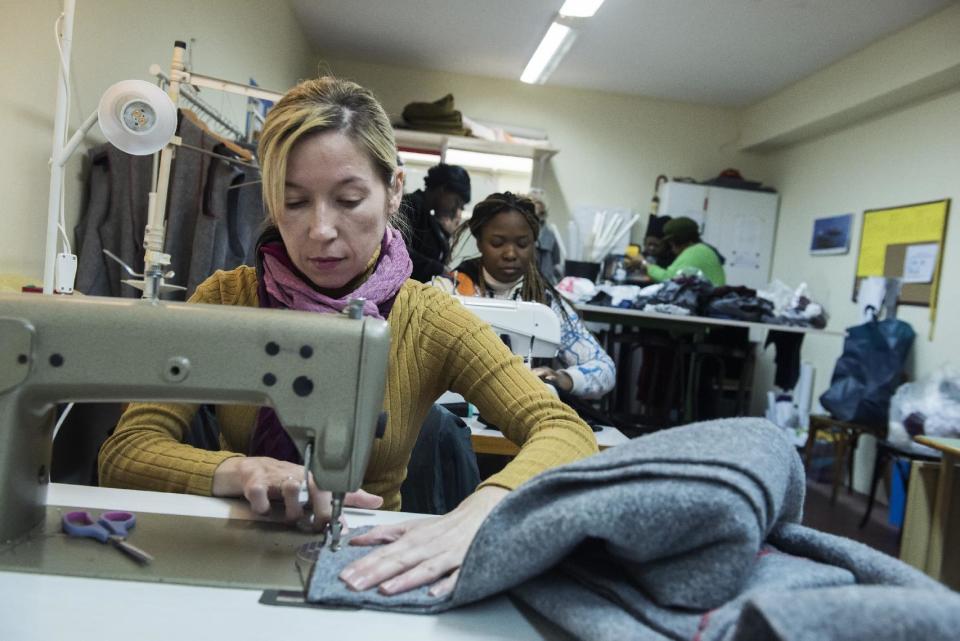 In this Monday, Jan. 30, 2017, a migrant sews a blanket, at a tiny coat workshop charity called Naomi in the northern Greek city of Thessaloniki, which is working long hours to collect and wash discarded blankets and turn them into wearable coats. The blankets are mostly army issue gray with red stitching and are distributed as aid at the sprawling refugee and migrant encampments, and are being recycled into practical coats for the vulnerable refugees who are facing a harsh winter. (AP Photo/Giannis Papanikos)