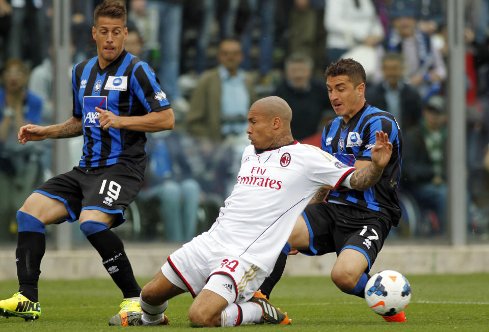 AC Milan's Nigel De Jong, center, of the Netherlands, fights for the ball with Atalanta's Carlos Carmona, right, of Chile, as Atalanta's German Denis, left, of Argentina, during a Serie A soccer match in Bergamo, Italy, Sunday, May 11, 2014. (AP Photo/Felice Calabro')