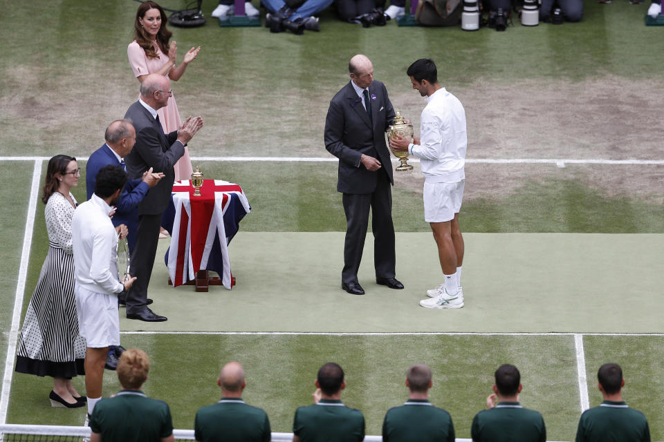 The Duke of Kent presents Serbia's Novak Djokovic with the winners trophy after he defeated Italy's Matteo Berrettini in men's singles final on day thirteen of the Wimbledon Tennis Championships in London, Sunday, July 11, 2021. At top left is Kate, Duchess of Cambridge. (Pete Nichols/Pool Via AP)