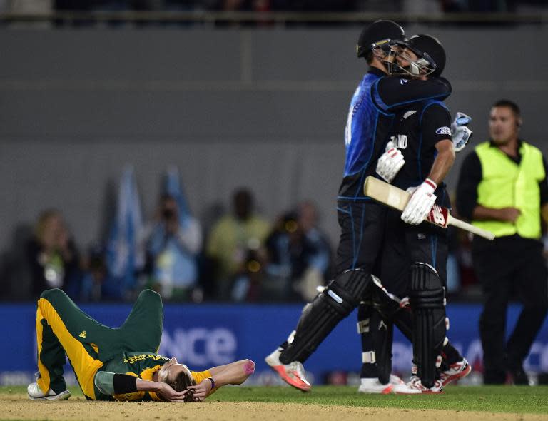 South African bowler Dale Steyn (L) lies on the ground dejected after his team's loss as New Zealand batsmen Grant Elliott (R) and Daniel Vettori celebrate after their Cricket World Cup semi-final match, at Eden Park in Auckland, on March 24, 2015