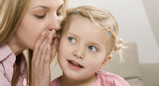 Mother whispering in daughter's (2-3) ear, close-up