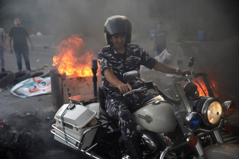 Lebanese police crosses a burning barricade on the highway at Nahr El Kalb