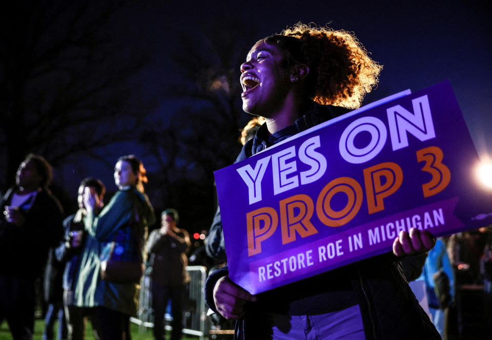 Jaelynn Smith holds a poster that says: Yes on Prop 3, Restore Roe in Michigan.