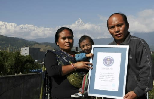 Khagendra Thapa Magar poses with his parents while holding his Guiness World Records certificate at their home in Pokhara in October 2010