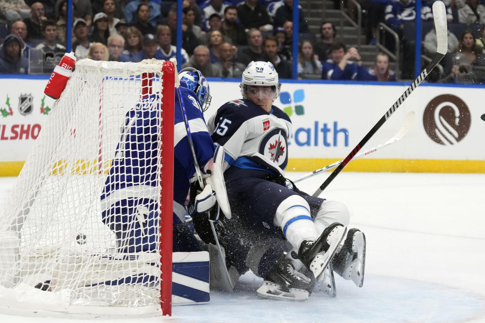 Winnipeg Jets center Mark Scheifele (55) gets pushed into Tampa Bay Lightning goaltender Jonas Johansson (31) during the first period of an NHL hockey game Wednesday, Nov. 22, 2023, in Tampa, Fla. (AP Photo/Chris O'Meara)