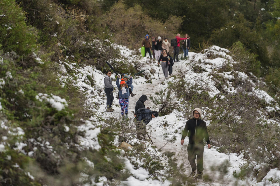 People walk along a trail partially covered in snow at the Deukmejian Wilderness Park, a rugged 709-acre site in the foothills of the San Gabriel Mountains, at the northernmost extremity of Glendale, Calif., Sunday, Feb. 26, 2023. (AP Photo/Damian Dovarganes)