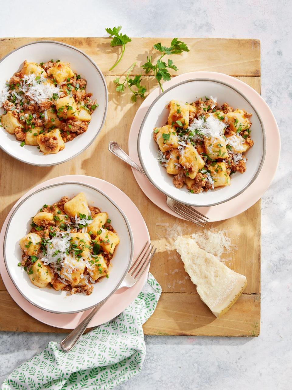 potato gnocchi with pork ragù in small plates on a cutting board with cheese