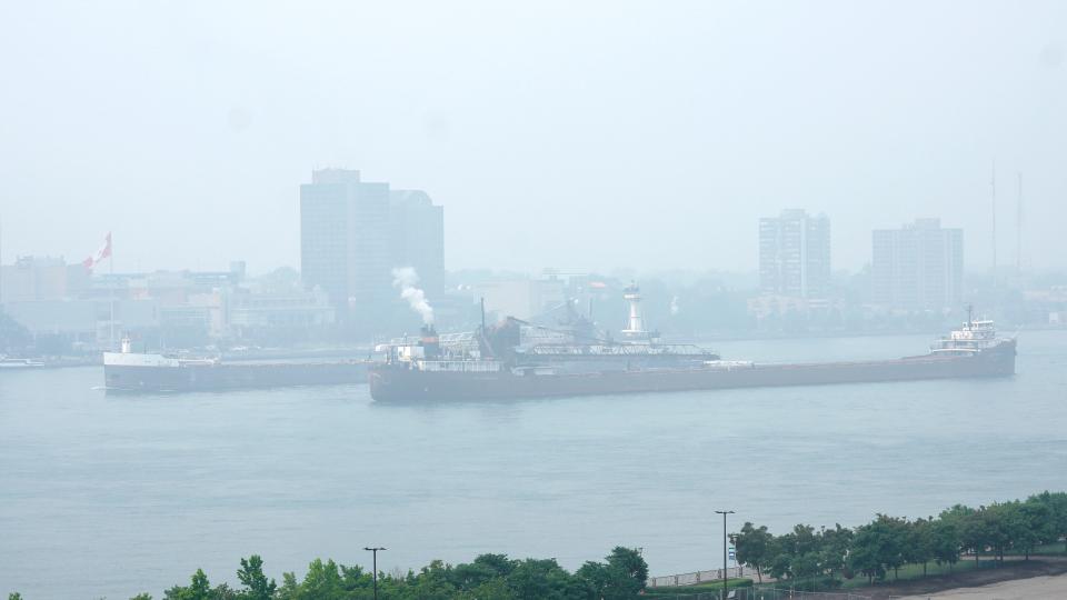 Freighters pass along the Detroit River with Windsor, Ontario, in the background as smoke fills the sky reducing visibility Wednesday, June 28, 2023, as seen from Detroit.