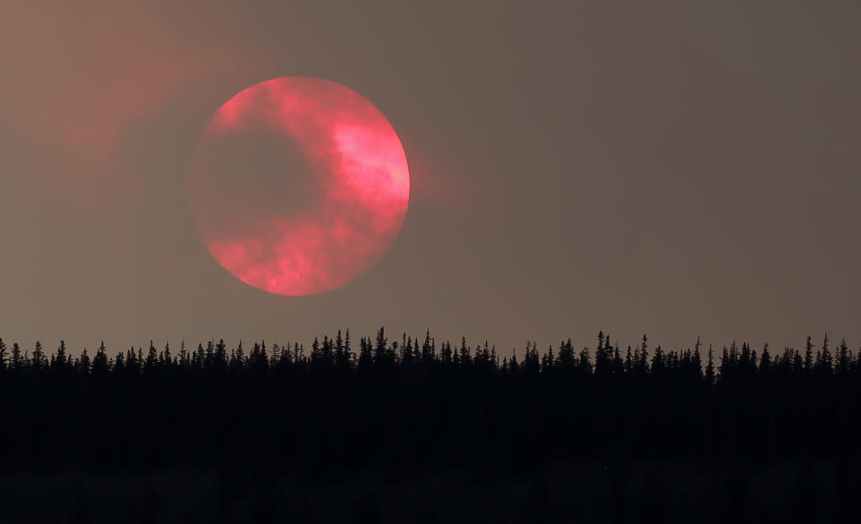 Wildfire smoke masks the sun as it sets over a ridge Saturday, June 22, 2013, near South Fork, Colo. Global warming is rapidly turning America into a stormy and dangerous place, with rising seas and disasters upending lives from flood-stricken Florida to the wildfire-ravaged West, according to a new U.S. federal scientific report released Tuesday, May 6, 2014. (AP Photo/Gregory Bull)