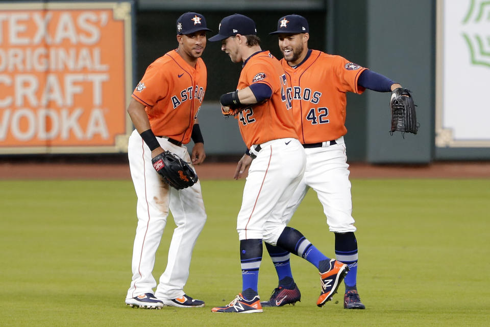 Houston Astros outfielders Michael Brantley, left, Josh Reddick, center, and George Springer, right, celebrate their win over the Oakland Athletics after the first baseball game of a doubleheader Saturday, Aug. 29, 2020, in Houston. All players and managers are wearing No. 42 as a tribute to baseball great Jackie Robinson. (AP Photo/Michael Wyke)