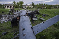 Oleksiy Polyakov, right, and Roman Voitko check the remains of a destroyed Russian helicopter lie in a field in the village of Malaya Rohan, Kharkiv region, Ukraine, Monday, May 16, 2022. (AP Photo/Bernat Armangue)