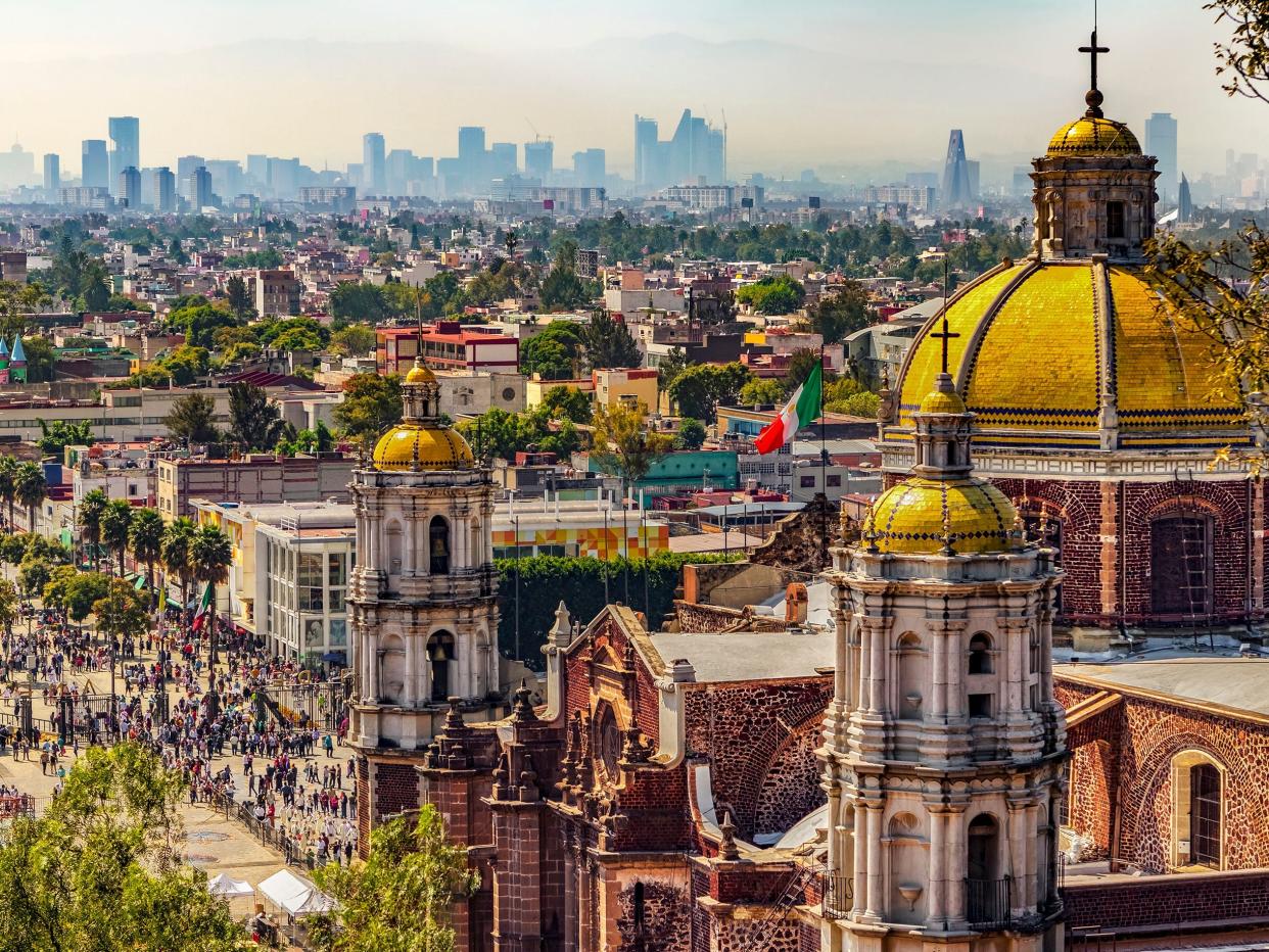 Mexico. Basilica of Our Lady of Guadalupe. Cupolas of the old basilica and cityscape of Mexico City on the far