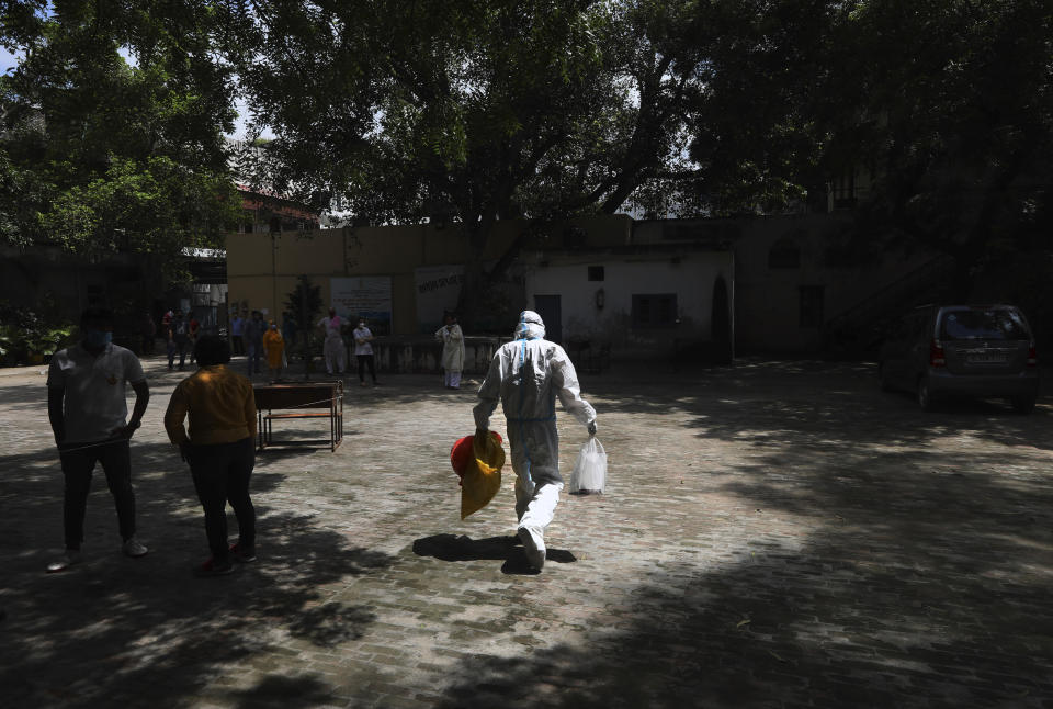 A health worker arrives at a makeshift center in a school to conduct tests for COVID-19 in New Delhi, India, Tuesday, Sept. 1, 2020. India has now reported more than 75,000 infections for five straight days, one of the highest in the world, just as the government began easing restrictions to help the battered economy. (AP Photo/Manish Swarup)