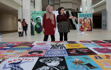 Isra Chaker (L) and Martha Neuman watch as a display of social justice images is assembled before the start of the three-day Women's Convention at Cobo Center in Detroit, Michigan, U.S., October 26, 2017. REUTERS/Rebecca Cook