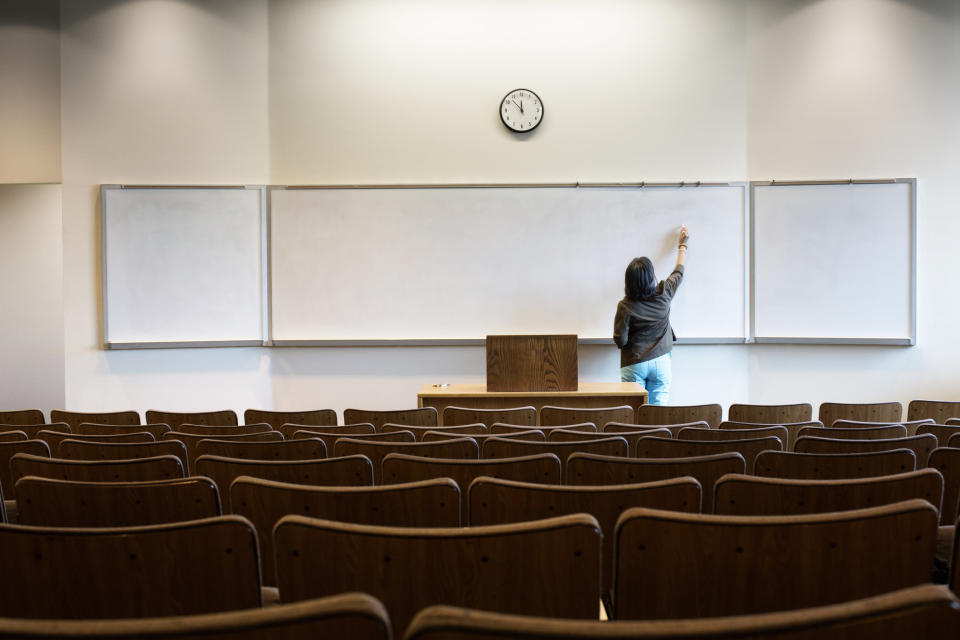 Someone writing on the board in an empty classroom