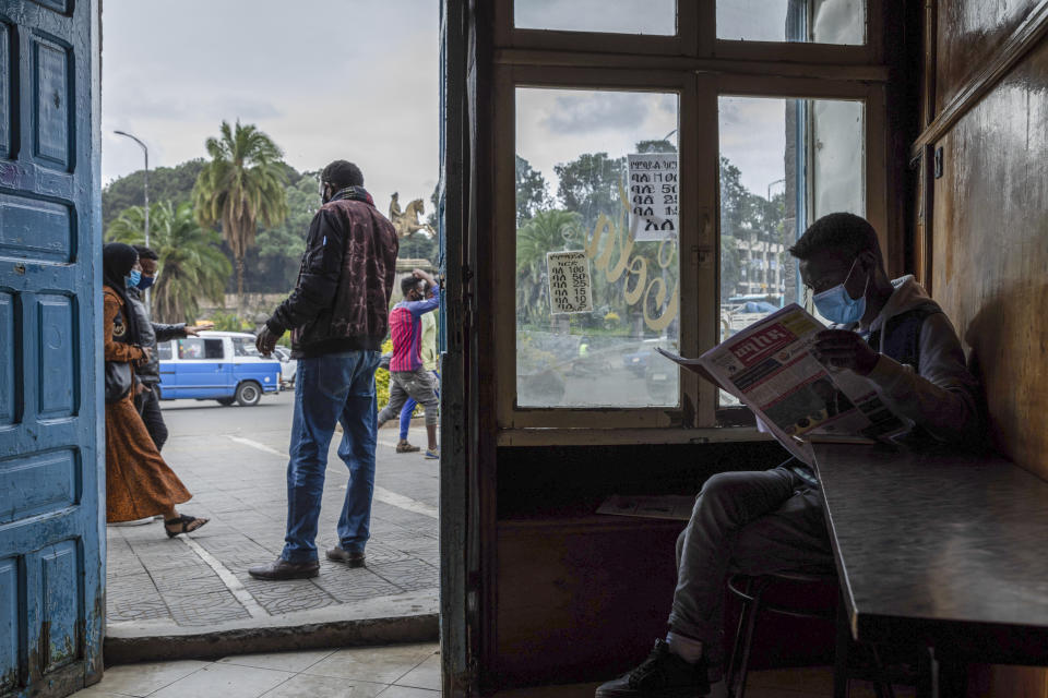 FILE - In this file photo dated Friday, July 17, 2020, a man wearing a face mask to curb the spread of the coronavirus reads a newspaper in a cafe in Addis Ababa, Ethiopia. A new report from the Ethiopian Human Rights Commission published Friday Jan. 1, 2021, says Ethiopian security forces killed more than 75 people and injured nearly 200 during deadly unrest in June and July after the killing of a popular singer. (AP Photo/Mulugeta Ayene, FILE)