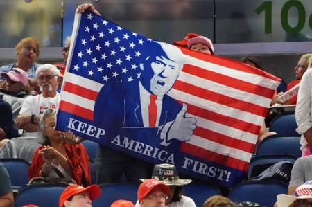 People sit in the stands with a flag before a rally for U.S. President Donald Trump at the Amway Center in Orlando