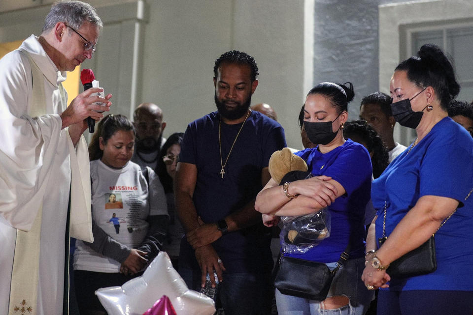 Father David Scotchie prays over Miya Marcano's parents during a vigil for the 19-year-old missing Valencia college student at Arden Villas, Friday, Oct. 1, 2021, in Orlando, Fla. Orange County Sheriff John Mina said Saturday that authorities found Marcano’s body near an apartment building. Marcano vanished on the same day a maintenance man improperly used a master key to enter her apartment. (Chasity Maynard/Orlando Sentinel via AP)