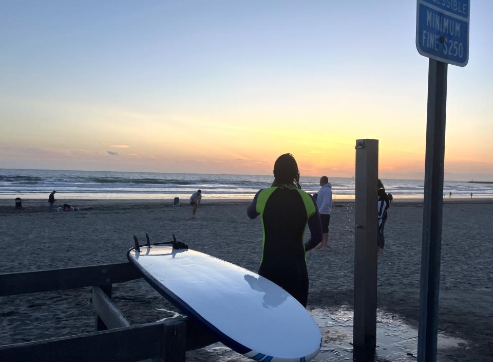 A surfer watches the sun set after riding the waves at Oceanside Harbor Beach. Oceanside, Calif., hosts major surfing events every year because of its consistent surf. Oceanside is an official training location of USA Surfing.