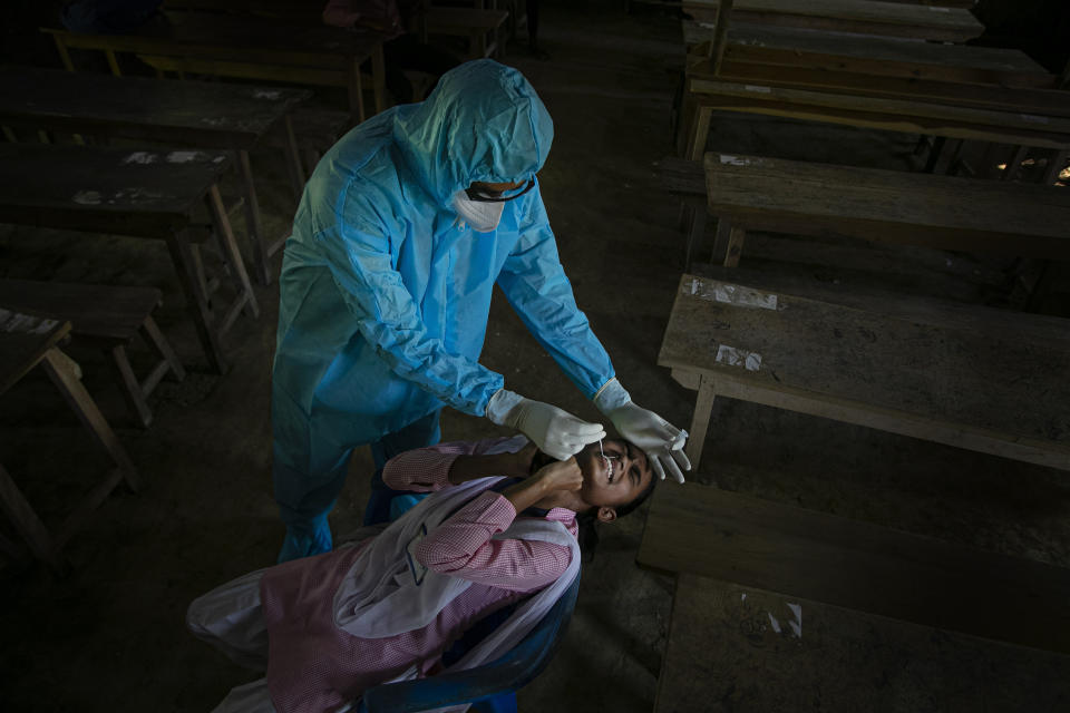 FILE - In this Sept. 30, 2020, file photo, an Indian health worker takes a nasal swab sample of a student to test for coronavirus after classes started at a college in Jhargaon village, outskirts of Gauhati, India. The global death toll from COVID-19 has topped 2 million. (AP Photo/Anupam Nath, File)