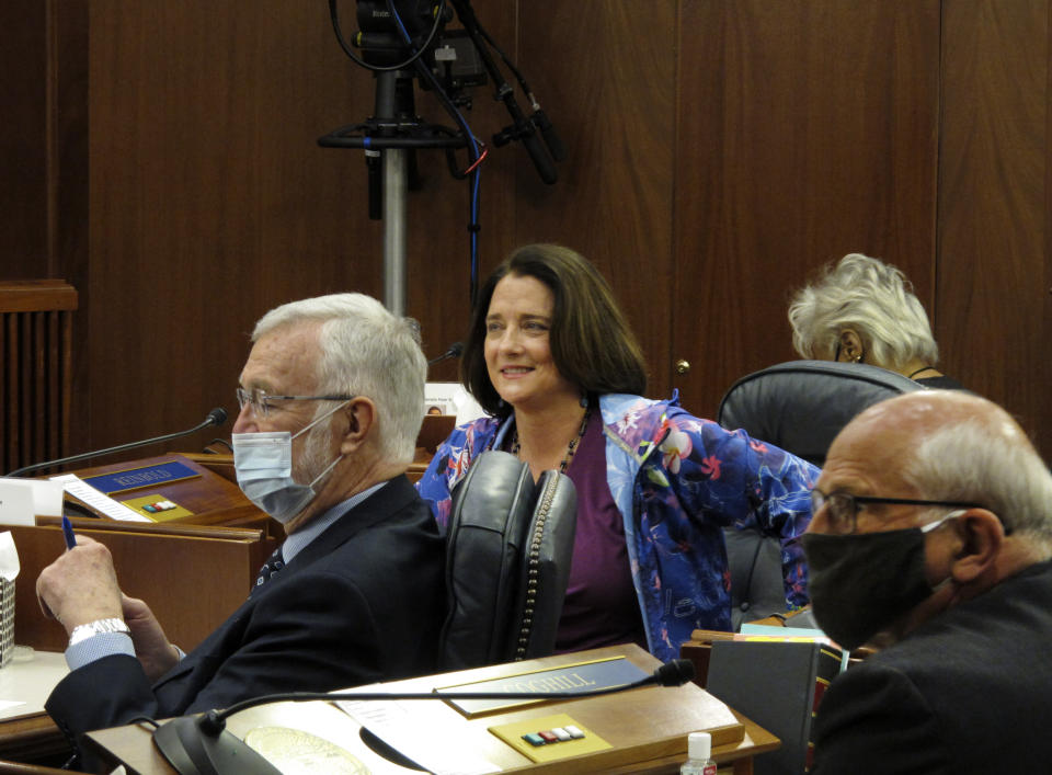 FILE - In this May 18, 2020 file photo, Alaska state Sen. Lora Reinbold, center, is shown on the Senate floor in Juneau, Alaska. The nation's ongoing battle against the coronavirus is dividing lawmakers along partisan lines in state Capitols. Health screenings were required of legislative staff and media at the Alaska Capitol, though lawmakers could skip it. Protocols said masks were required. But Reinbold didn't wear one. “It didn’t make sense to me,” Reinbold said. "I saw no research on cloth, silk, cotton face coverings ... that they prevent COVID.” (AP Photo/Becky Bohrer, File)