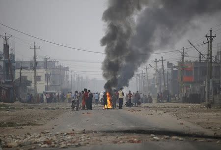 Protesters stand near burning tyres as they gather to block the highway connecting Nepal and India, during a general strike called by Madhesi protesters demonstrating against the new constitution in Birgunj, Nepal November 5, 2015. REUTERS/Navesh Chitrakar