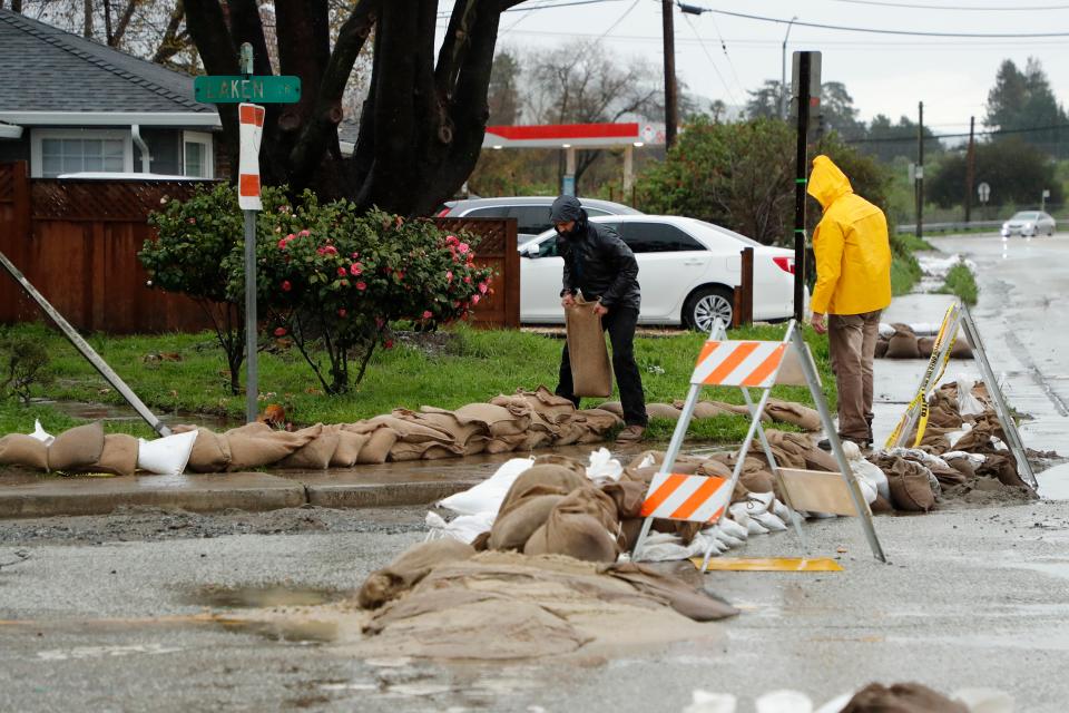 Residents stack sandbags around a home and along a neighborhood street in preparations for flooding from the next wave of storms (EPA)